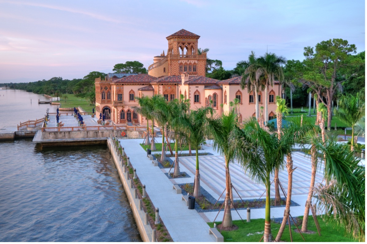 The Ringling Museum along the bay with palm trees and greenery in front.